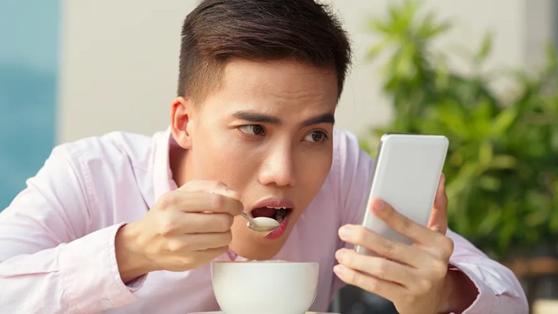 Seorang pengguna yang sedang nyaman dan fokus membaca informasi dari layar smartphone-nya yang responsif.