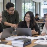 Mahasiswa Magister Manajemen belajar dengan laptop dan materi perkuliahan.